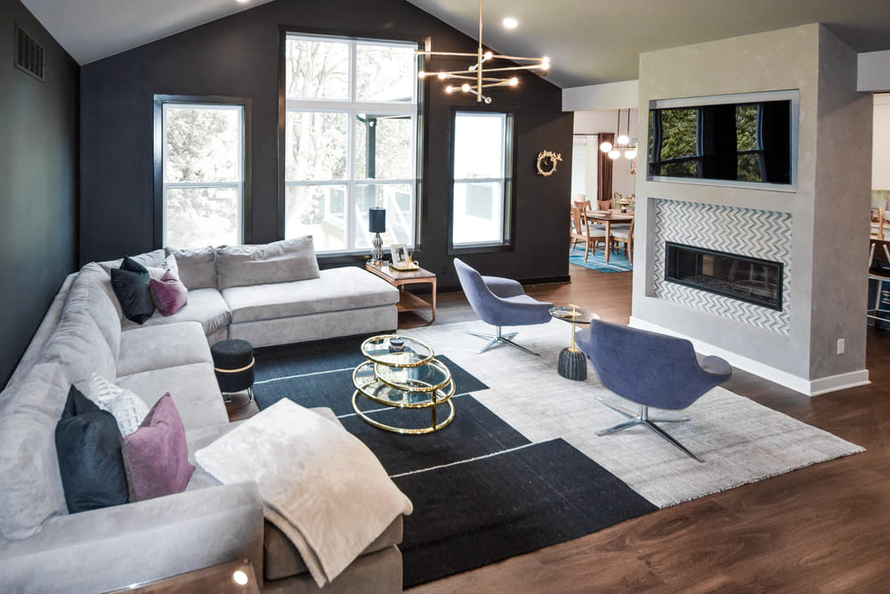 living room with black walls and modern gold chandelier and gas fireplace by chris gorman homes in cincinnati